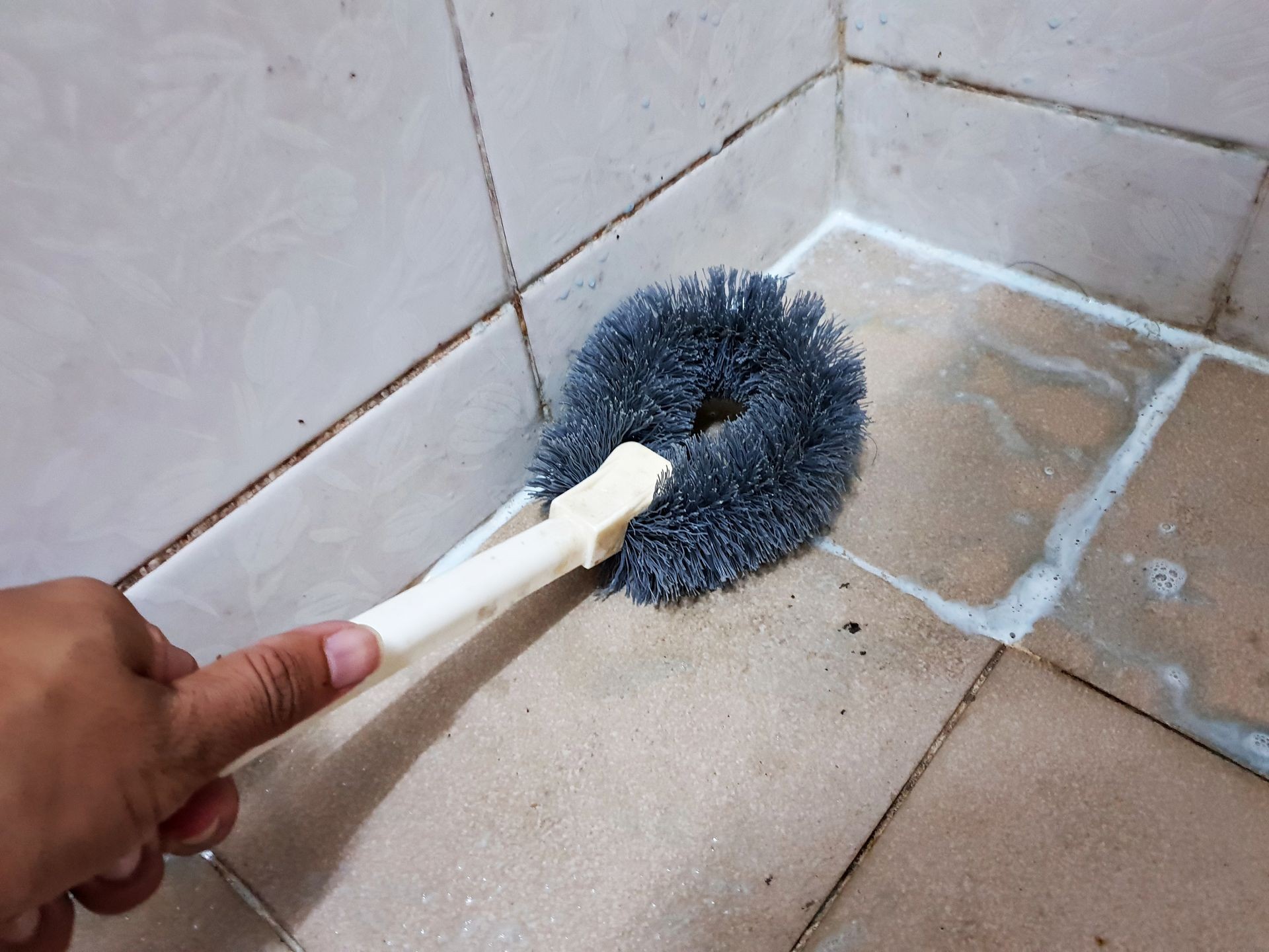 Cleaning brushes and bathroom cleaning liquid over detail of dirty stain floor in restroom.
